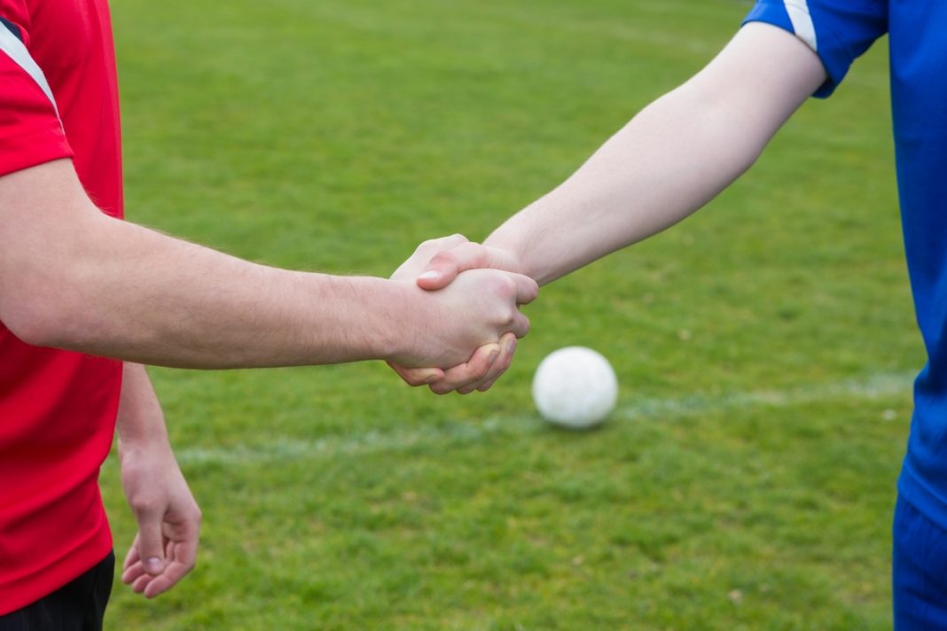 Football players in blue and red shaking hands