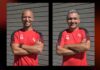 FC Küssnacht setzt weiter auf Trainerduo Sorrentino/Ordonez Two men in red sports shirts with black sleeves stand side by side, arms crossed, smiling in front of a gray wooden wall; initials 'SS' and 'RO' appear on their chests.