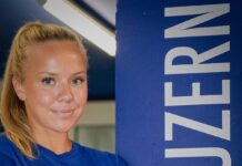 FCL: Mehrere Vertragsverlängerungen im AWSL-Team Smiling young woman with blonde hair in a blue shirt stands beside a tall blue column that reads 'LUZERN' vertically.