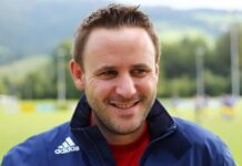 Neuausrichtung bei Brunnen II: Neuer Trainerstaff übernimmt Smiling man in a blue Adidas jacket outdoors on a sports field.