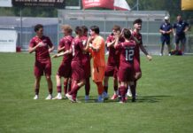 Torreiches Testspiel: Perlen-Buchrain und Emmen trennen sich 3:3 Group of soccer players in maroon uniforms huddle and high-five on a sunny green field, with an orange-clad goalkeeper nearby.