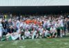 SC Kriens mit attraktiven Saisonkarten Group of soccer players and staff posing on the field with medals and a trophy after a win, stadium stands in the background.