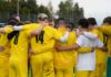 FC Hitzkirch gewinnt die IFV-Wertung der Fairplay-Trophy Soccer team in yellow uniforms huddles with arms around each other on a grassy field, seen from behind.