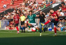 Später Sturmlauf bleibt unbelohnt: Kriens verpasst Punktgewinn knapp Soccer match action: green player and red-black player contest a high ball near the sideline with a crowd in the stands behind them.