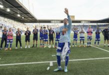FCL: Andrej Vasovic wechselt zu Club Brügge Soccer players in blue kits stand in a line on the field applauding as a teammate raises his right hand in celebration at the stadium edge.