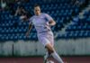 Cristina Carp verlässt den FC Luzern Female soccer player in a light purple uniform dribbles a ball on a grass field, with blue stadium seats in the background.