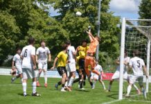 Stirbt die Kategorie der A-Junioren auch im IFV-Gebiet aus? Soccer game near the goal with an orange-clad goalkeeper jumping to punch the ball away amid white and yellow players nearby.