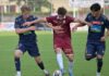 FC Luzern U21 mit geglückter Hauptprobe Three soccer players in blue and maroon kits compete for the ball on a green field during a match, with the central maroon player shielding the ball from two opponents.