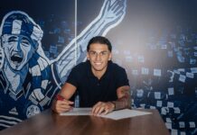 FCL: Lucas Manuel Silva Ferreira verlängert vorzeitig Young man smiles while signing a document at a table, blue mural backdrop behind him
