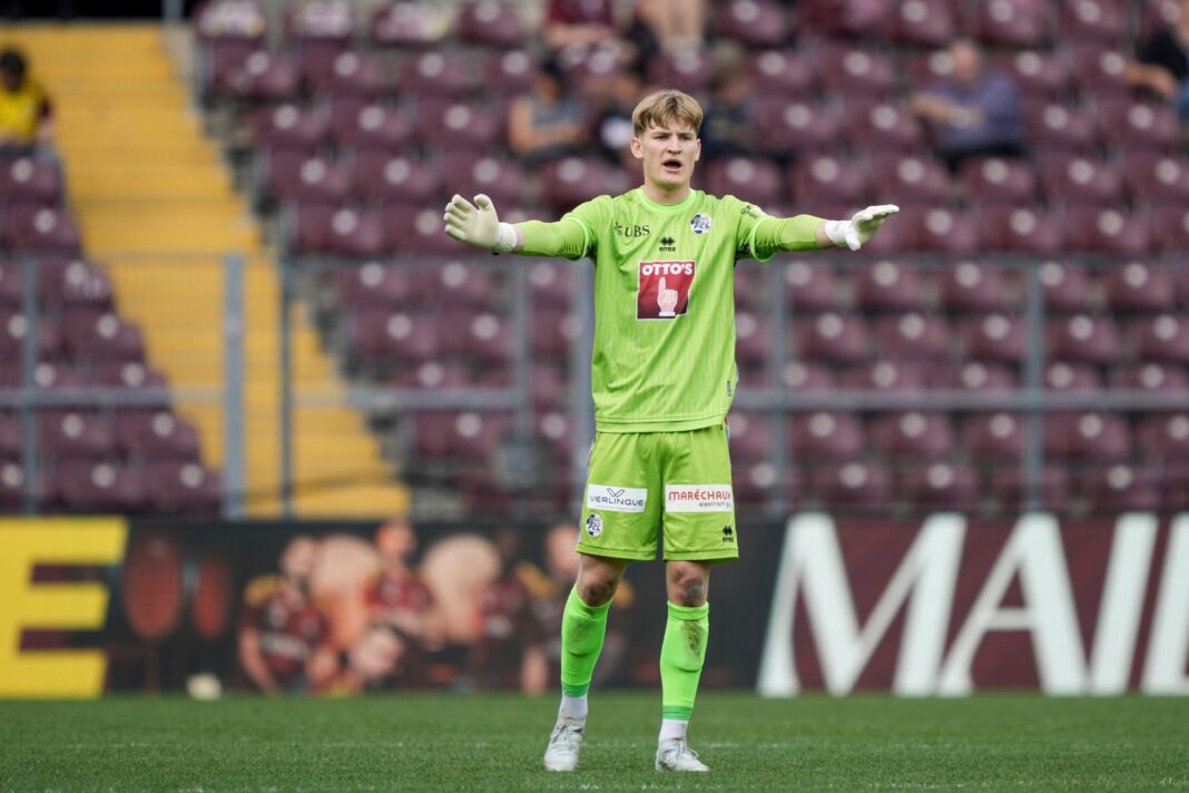 mme_20260406_servette_luzern_05420_1 Soccer goalkeeper in neon green kit stands with arms outstretched on the pitch during a match.