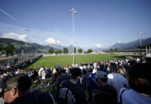 Anpfiff-Fieber im Schweizer Cup: Die Zentralschweizer Teams kennen ihre Spielzeiten Crowd watching a daytime soccer match at a sunny stadium with green field and mountain backdrop.