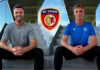 Cham verstärkt sich weiter Two athletes sit on concrete stadium steps with hands clasped, SC Cham crest centered between them behind.