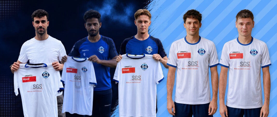 Five young men pose as a soccer team, holding up their new white jerseys with blue trim and sponsor logos.