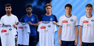 Five young men pose as a soccer team, holding up their new white jerseys with blue trim and sponsor logos.
