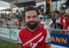Buttisholz siegt verdient gegen Wauwil-Egolzwil Bearded man in a red and white diagonal-striped sports jersey stands in front of spectators at an outdoor stadium.