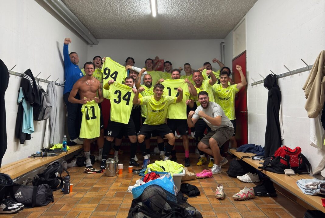 33236 Soccer team in a locker room celebrating, wearing bright yellow jerseys and posing with fists up.