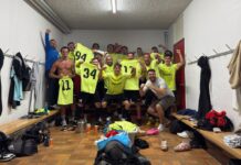 FC Emmenbrücke a mit spektakulärem 4:3-Sieg Soccer team in a locker room celebrating, wearing bright yellow jerseys and posing with fists up.