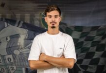 Defensive Verstärkung für den SC Kriens Man with brown hair and light stubble, arms crossed, wearing a white T-shirt, posing in front of a green/black checkered sports banner.