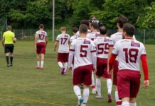 Rothenburg unterliegt effizienten Willisauern Soccer players in white and maroon uniforms walk onto the field from the back, heading toward play.