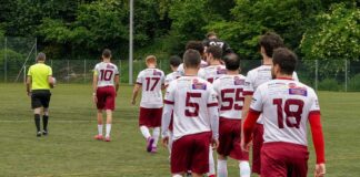 Soccer players in white and maroon uniforms walk onto the field from the back, heading toward play.