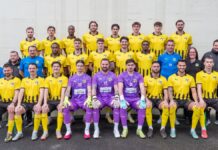 FC Emmenbrücke: Es kann ja nur noch besser werden Group portrait of a soccer team in yellow and black kits, with four goalkeepers in purple jerseys seated in front row.