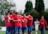Tia schiesst Cham zum Auftaktsieg Soccer players in red jerseys huddle together on a green field before a game.