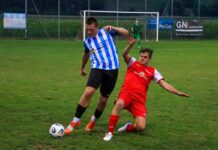 Dagmersellen startet mit überzeugendem Heimsieg gegen Zell Soccer players contest the ball on a grassy field near the goal; blue-and-white striped player shields the ball from a red opponent.