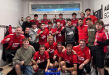 Schattdorf startet mit Heimsieg gegen Baar Handball team of about 20 players in red jerseys posing in a locker room, many holding beer bottles and smiling after a game.