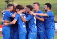 Küssnacht wird für engagierten Auftritt in Willisau nicht belohnt Soccer players in blue jerseys form a huddle, arms around each other in celebration on a field