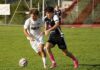 Heimserie endet nach 350 Tagen – Perlen-Buchrain verliert gegen Hergiswil Two soccer players chase a ball on a green field, one in white and one in black, near a goal in the background.