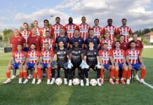 Saisonvorschau FC Rotkreuz: Eine Mannschaft, ein Weg, ein Ziel Group of soccer players and coaches pose for a team photo on a green field, wearing red-and-white striped uniforms and blue shorts on a sunny day.