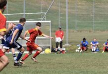 Escholzmatt-Marbach mit Derby-Sieg gegen Wolhusen Youth soccer match: a player in red chases a ball near the goal area with blue-clad opponents close behind on a grassy field.