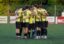 Bittere Heimpleite: Eschenbach belohnt sich wieder nicht Soccer players in yellow jerseys form a tight huddle on a green turf field, arms around each other before the game.