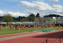 Baar entführt drei Punkte aus Willisau Soccer players in red and yellow uniforms walk in a line across a grass field beside a running track.
