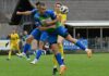 ESC Erstfeld: Remis gegen Steinhausen trotz starker Schlussphase Two soccer players leap for the ball in mid‑air during a match on a grassy pitch, with a yellow‑kit opponent nearby.