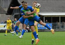 ESC Erstfeld: Remis gegen Steinhausen trotz starker Schlussphase Two soccer players leap for the ball in mid‑air during a match on a grassy pitch, with a yellow‑kit opponent nearby.