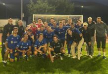 Ausrufezeichen gesetzt: Küssnacht mit klarem Heimsieg gegen Schattdorf Group of soccer players and staff posing for a team photo on a grass field at night, all wearing blue uniforms with a sponsor logo.