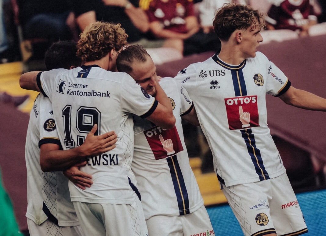 fcluzern Soccer players in white jerseys embrace in celebration on the field.