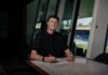 FC Luzern verpflichtet Tim Hottiger Man smiling while signing documents at a marble table inside a modern building, using a red pen.