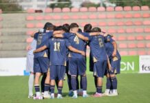 Frühe Hypothek wiegt schwer: FCL U21 bleibt gegen Brühl ohne Punkte Soccer players in blue uniforms huddle with arms around each other on a grass field in a stadium with red seats behind them