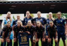 FCL: Sarah Schildknecht fällt mit schwerer Knieverletzung aus Group portrait of female soccer players in blue uniforms posing together on the field, stadium seating in the background, with player wearing jersey #19 Schildknecht in front.
