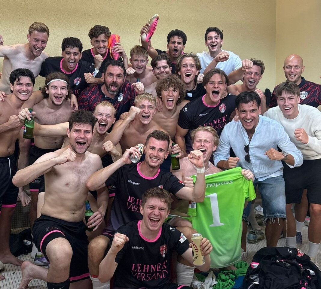image1 (2) Group of smiling athletes celebrating in a locker room, many shirtless, some in black-pink uniforms, holding drinks and a green jersey with number 1 visible.